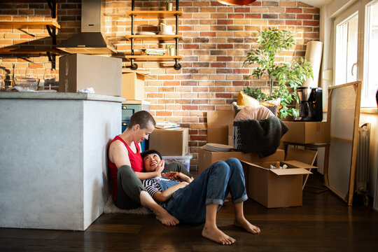 Couple relaxing on floor amid moving boxes at home