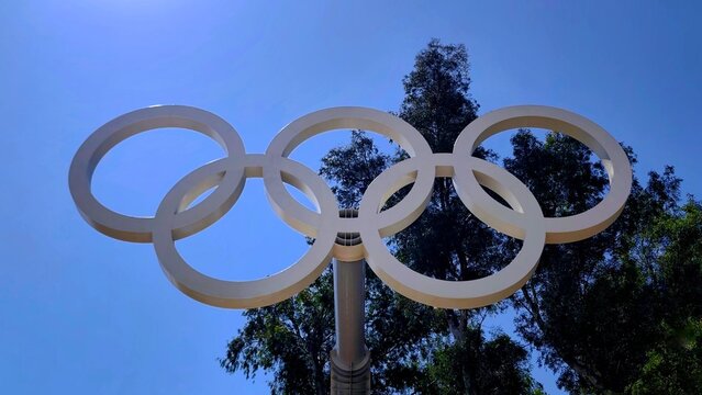 Low-angle view of the Olympic rings sculpture rising above the historic all-marble Panathenaic Stadium (Kallimarmaro), one of Athens' most iconic landmarks.