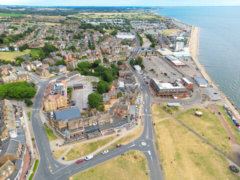 Dramatic drone view of the famous seaside town of Hunstanton, Norfolk, UK. Showing distance arcades and a fun fair along the beach coastline. Nearby the town centre and green space, seen in summer.