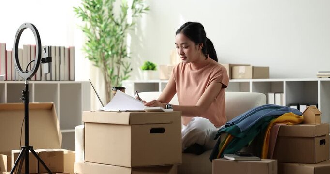 Asian woman calculating orders and preparing packages for online selling