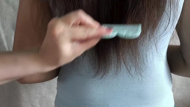 Close up of hairstylist combing the ends of long hair before haircut, damaged hair treatment and salon service concept.