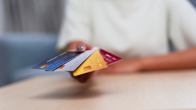 Individual presenting various credit cards on a wooden surface within a contemporary indoor environment