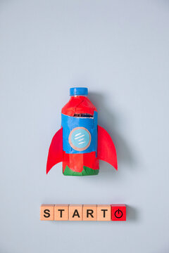 Creative startup concept with handmade rocket, wooden START blocks on blue background, symbolizing business growth, innovation, entrepreneurship, motivation, success.