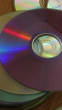 Compact discs with colorful reflections on wooden table