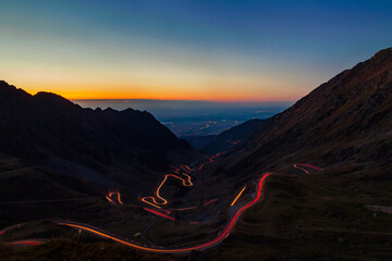 Transfagarasan road winding through mountains at dusk with light trails © Chris M