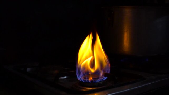 Natural gas flame burning blue and yellow on kitchen stove burner at night fire cooking energy