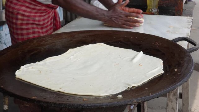 Large flatbread cooking on hot griddle by chef