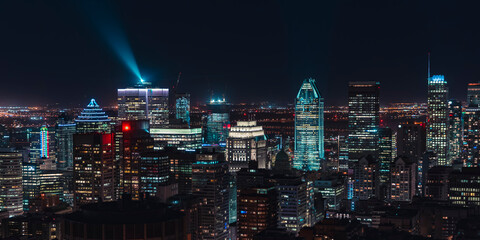 Montreal downtown skyline illuminated at night with glowing skyscrapers and a bright light beam over the financial district, Quebec, Canada © Shawn M. Kent