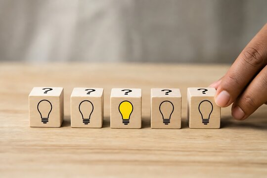 Hand selecting a glowing light bulb wooden block among others with question marks