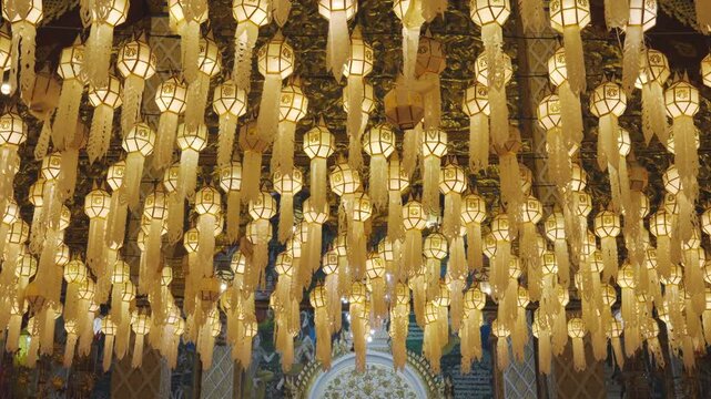 Zoom out Northern Thai Lanna lanterns at an annual light festival glow brightly, symbolizing faith in the Buddhist way of life.