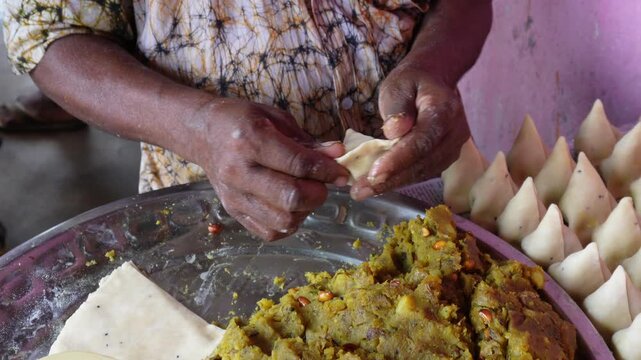 Person preparing crispy samosas with fresh spiced potato filling