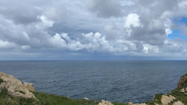 Wide view of the Atlantic Ocean beneath beautiful cumulus clouds with calm water and a distant horizon. Static coastal landscape footage with natural light and a peaceful atmosphere.
