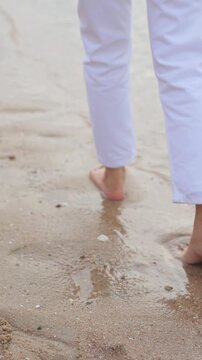 Barefoot walking along a peaceful beach shoreline with gentle ocean waves,