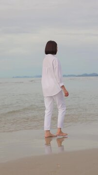 Barefoot walking along a peaceful beach shoreline with gentle ocean waves,