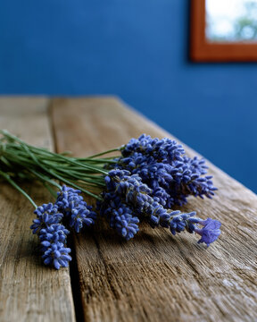 Fresh lavender flower bouquet on rustic wooden table, blue wall background, natural light, calming mood, aromatic herb, countryside style