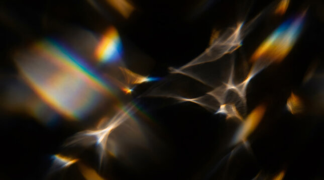 Abstract light leaks and rainbow prismatic lens flare on black background