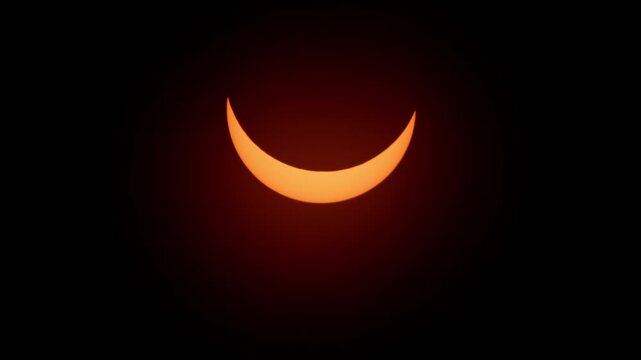 Dramatic view of the partial solar eclipse on April 8, 2024 over Halifax, Nova Scotia. The sun transforms into a glowing crescent shape in the clear sky, unforgettable astronomical moment 4K.