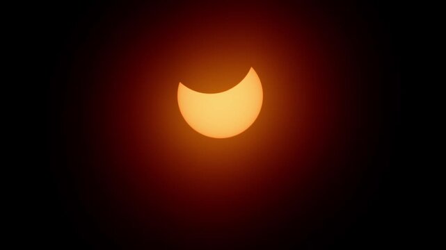 Beautiful partial solar eclipse captured in Halifax, Nova Scotia on April 8, 2024. The sun appears as a brilliant glowing crescent against the blue sky, dramatic astronomical moment in Canada 4K.