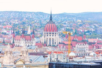 Obraz premium Budapest provides a breathtaking urban landscape featuring prominent dome of Hungarian Parliament Building. Classic architectural spires and red rooftops fill city panorama under overcast sky