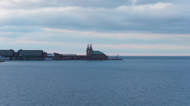 Calm water of Lake Michigan surrounding Jardine Water Purification Plant and Navy Pier in Chicago, Illinois, with city buildings along coastline on overcast day