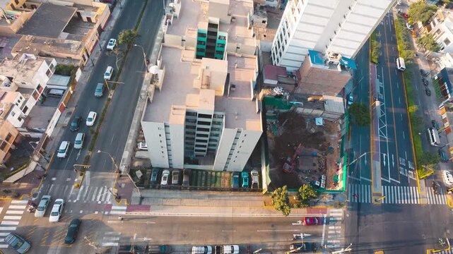 High-angle timelapse of an urban construction site with active machinery and bustling city traffic