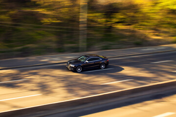 Naklejka premium Dark car driving fast on highway road