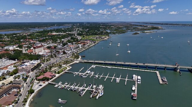 Aerial view of the Bridge of Lions spanning the Matanzas River with a bustling marina filled with boats and the historic cityscape of St. Augustine, Florida, United States.