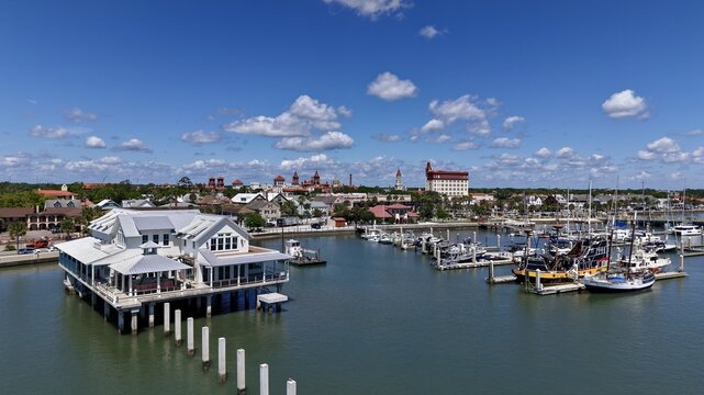 Aerial view of the waterfront in St. Augustine, featuring a white building on stilts, a marina with boats, and the historic city skyline, St. Augustine, Florida, United States.