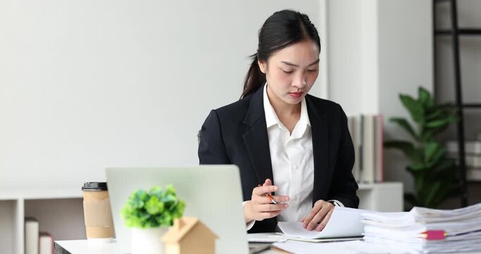 Businesswoman concentrating on a large stack of documents, managing heavy workload