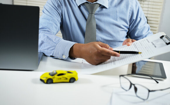 A car sales office and a salesperson are negotiating a car title. Explaining the car business agreement documents. Car sales. Selling and leasing cars with insurance.

