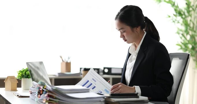 Businesswoman concentrating on a large stack of documents, managing heavy workload