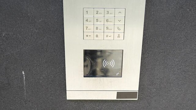 Person using contactless key fob on residential building access control system. Secure entry technology supports convenient and controlled property access