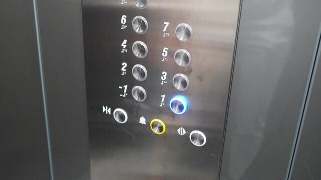 Person pressing the first floor button inside a modern residential elevator. Everyday elevator use supports convenient access and efficient movement between building levels