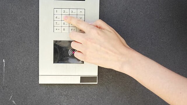 Person entering numbers on residential building intercom keypad. Secure access control enables visitor communication and controlled building entry