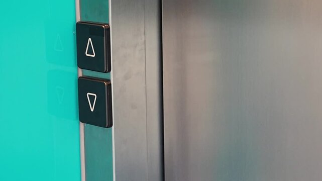 Person pressing elevator call button in modern residential building and entering the elevator. Everyday accessibility and vertical transportation improve convenience and mobility