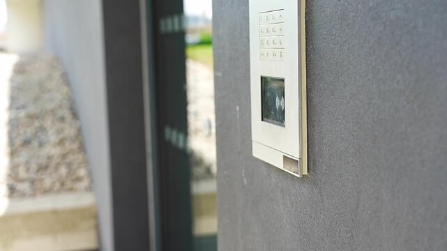 Person using contactless key fob on residential building access control system and entering the building. Secure entry technology supports convenient and controlled property access