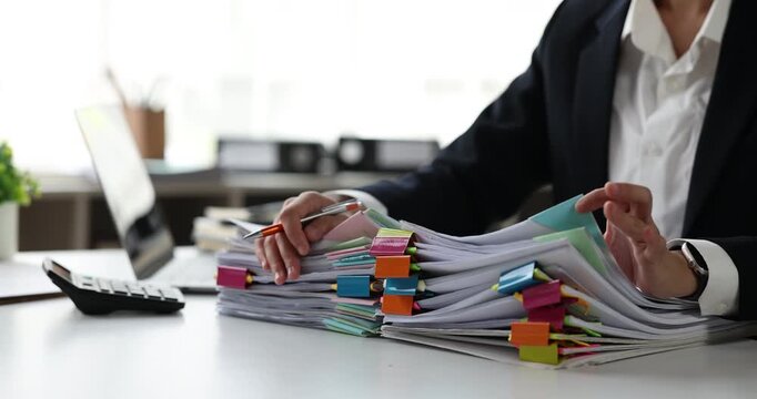 Professional businesswoman organizing a large stack of documents, highlighting a busy office workload