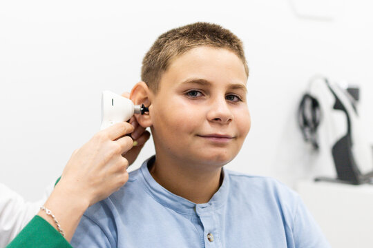 A child undergoes a hearing test with a digital otoscope at a medical center while looking at the camera. Concept of hearing prevention in young children.