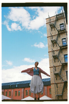 Model poses outside a building with fire escapes in an urban setting