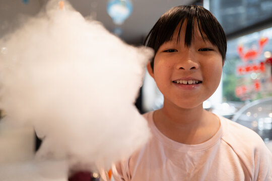 Child Enjoys Cotton Candy Treat Inside Busy Cafe