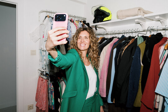 Woman takes a selfie in a colorful fitting room with bright clothes