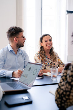 Cheerful woman is listening to colleagues at meeting 