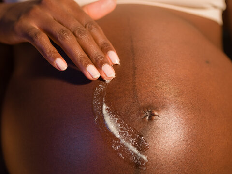 Woman doing skincare on pregnant belly
