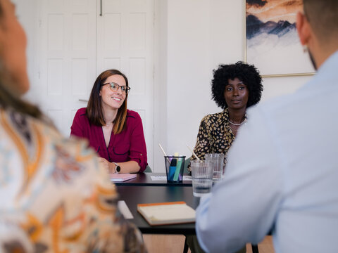 Smiling women listening to colleague at meeting 