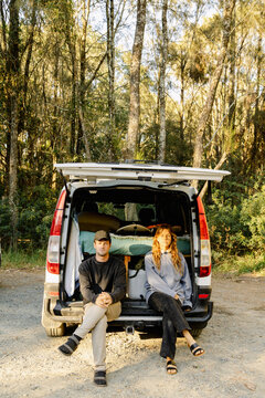 UGC couple sitting at open campervan on autumn forest road trip