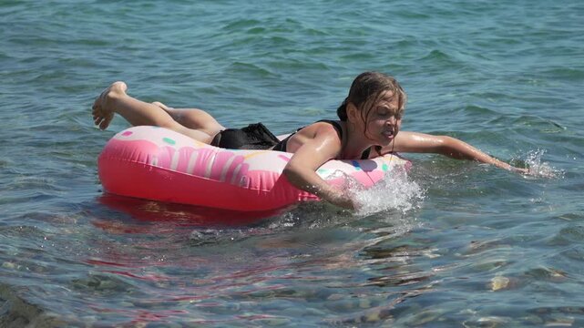 Girl swimming pool inflatable floating on ocean surface enjoying summer holidays in turquoise clear water at beach on a sunny day