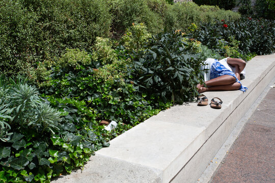 Femme allong&eacute;e et dormant sur un muret dans la rue