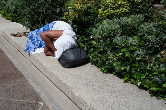 Femme allong&eacute;e et dormant sur un muret dans la rue