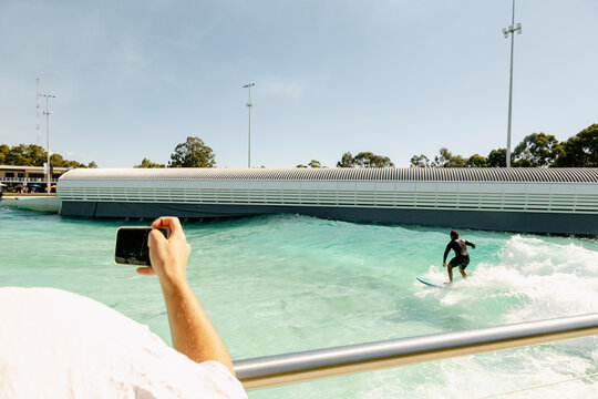 UGC person filming surfer at outdoor wave pool