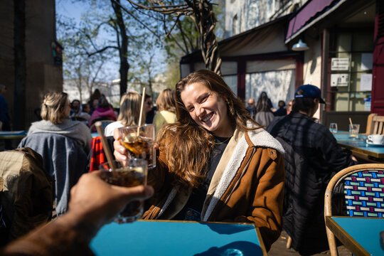 Young woman smiling and making a toast at a Paris cafe terrace